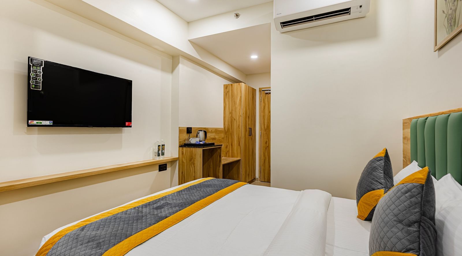Lemonridge Hotels, KPHB | Hotel room featuring a bed with a grey and yellow carpet, and a dark headboard. Modern style.